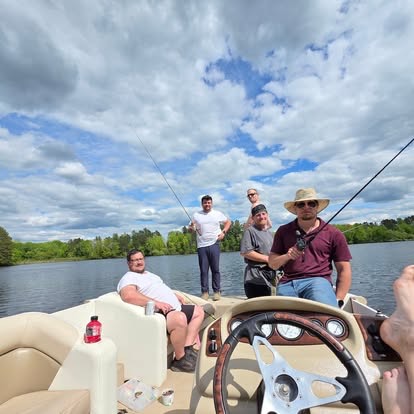 Several men fishing from a pontoon boat on a sunny northern Wisconsin lake under a bright blue sky.