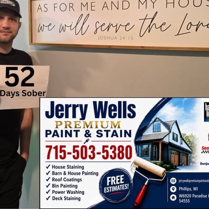 A man holding a 52 Days Sober sign beside a Jerry Wells Premium Paint and Stain sponsor banner.