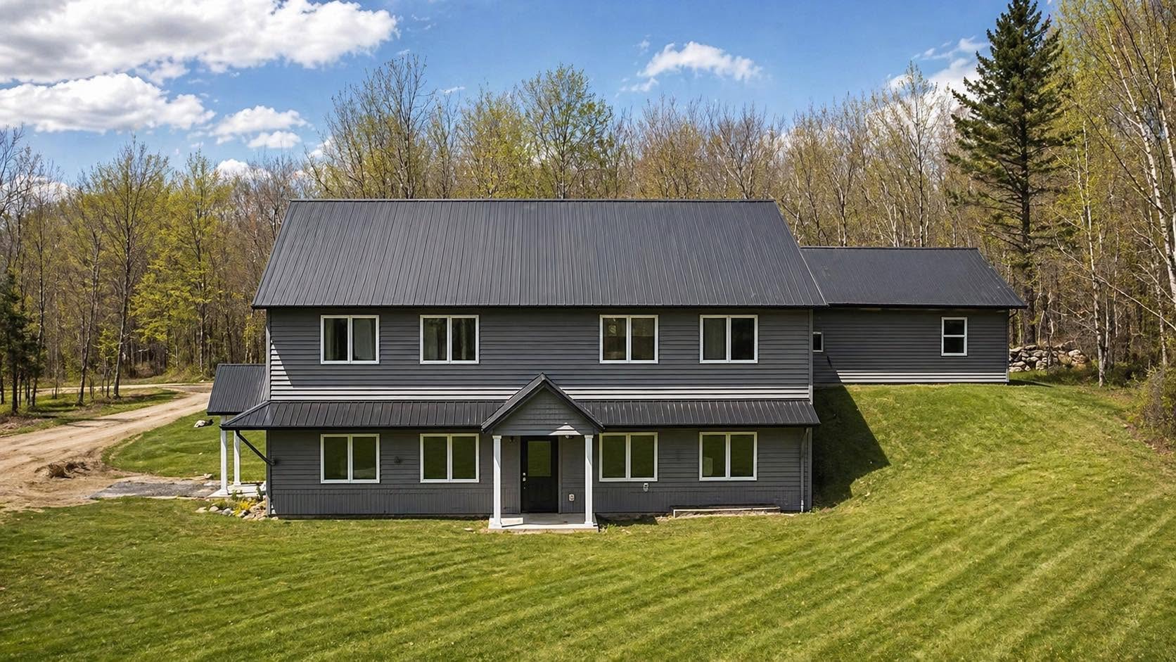 The His House of Hope residential home, a large two-story house with gray siding and a dark metal roof, set on a green lawn in wooded northern Wisconsin
